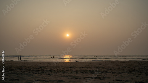 Sunset over sea and beach. Cloudless sundown sky over waving sea and sandy beach in evening on resort © Anton Dios
