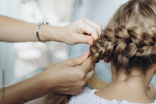 Mother do hair braid to her daughter, close up photo