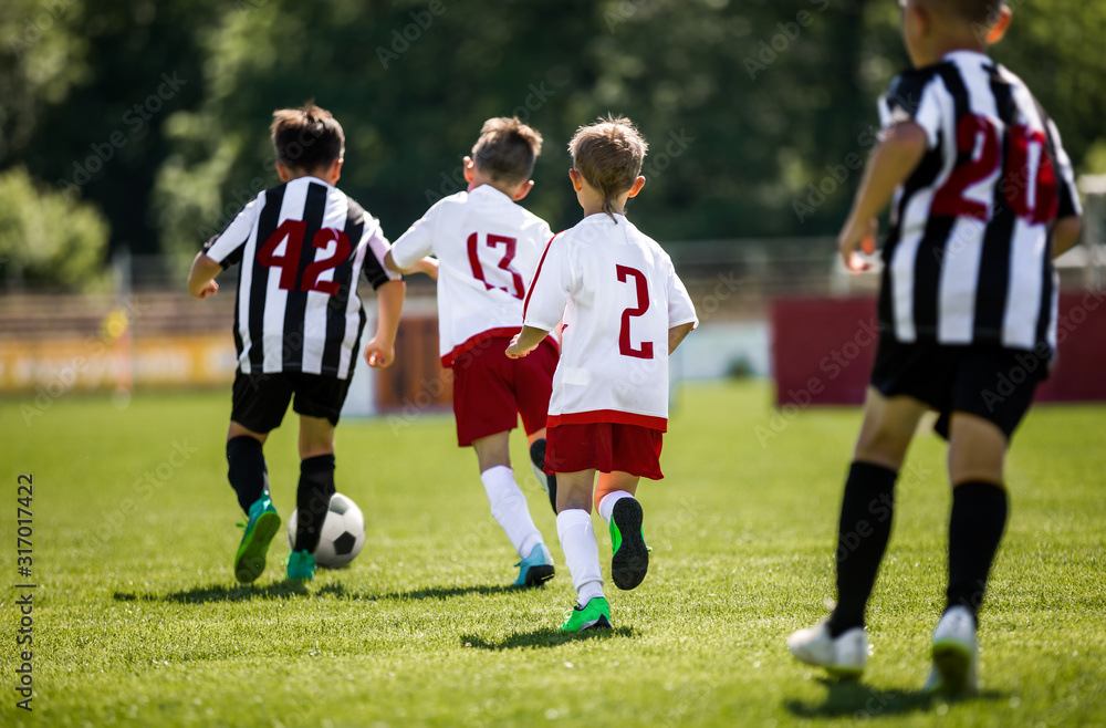 Young Boys In Football Teams Running in Duel After Soccer Ball Young Boys In Football Teams Running in Duel After Soccer Ball