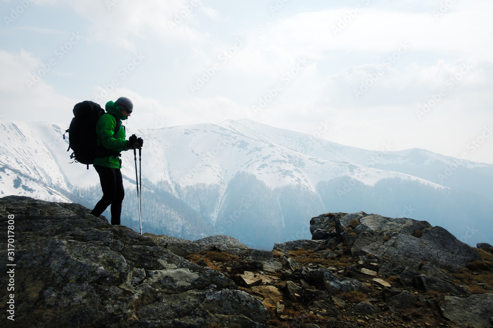 Hiker with backpack silhouette on snowy mountains range background