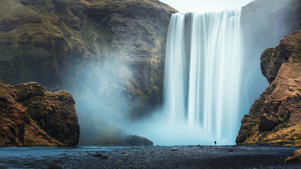 Alone tourist overlooking waterfall at Skogafoss, Iceland
