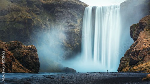 Alone tourist overlooking waterfall at Skogafoss  Iceland
