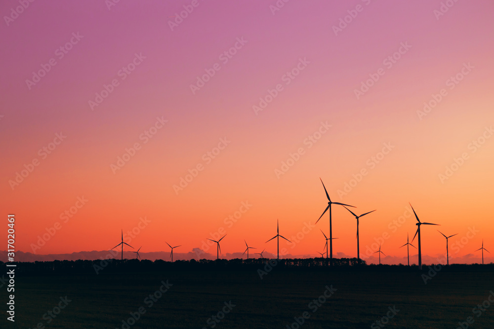 Wind turbines against beautiful sunset sky. Eolic park. Eco farm of clean energy.