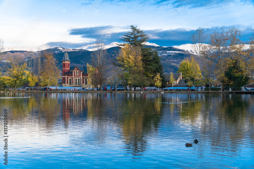 Fototapeta premium Puigcerdà, Catalonia / Spain. Lake of Puigcerdà with Villa Paulita and the snowy Pyrenees in the background