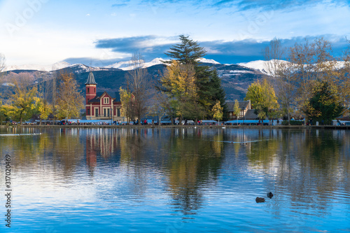 Puigcerdà, Catalonia / Spain. Lake of Puigcerdà with Villa Paulita and the snowy Pyrenees in the background