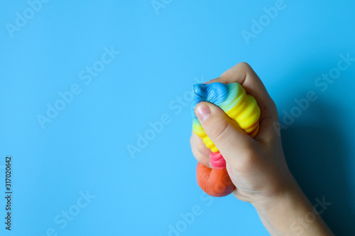 anti stress squishy toy in the form of multicolored ice cream in children's hands on blue background. space for text