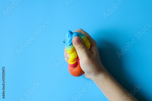 Photos anti stress squishy toy in the form of multicolored ice cream in children's hands on blue background