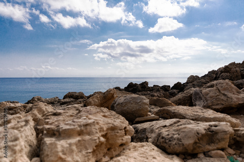 Mediterranean Sea in Northern Cyprus. Summer rocky coast  transparent calm blue water and white clouds on blue sky. Seascape.