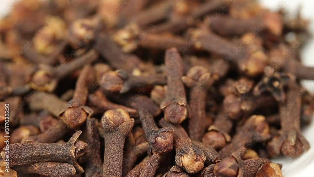 Dry cloves fall into a glass transparent bowl, close-up Dry cloves fall into a glass transparent bowl, close-up