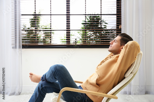 Attractive man relaxing in armchair near window at home