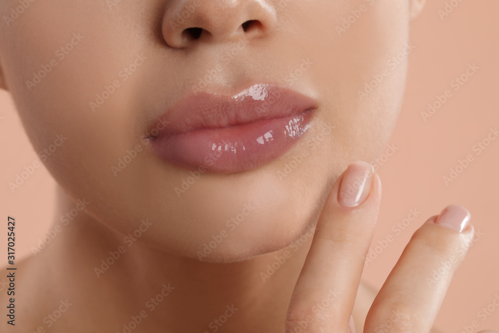 Fototapeta premium Young woman with beautiful full lips on peach background, closeup