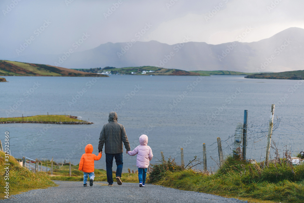 father with son and daughter walking to sea shore father with son and daughter walking to sea shore