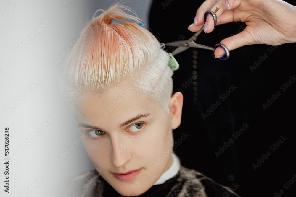 Obraz premium Hairdresser machine cuts woman client. A short haircut, shaved temple and a drawing on the hair.