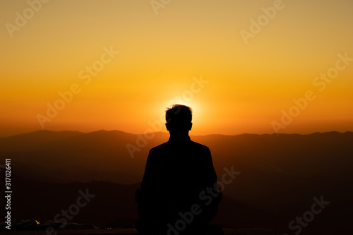 Image of Silhouette meditation yoga practicioner during sunset on highest mountain.