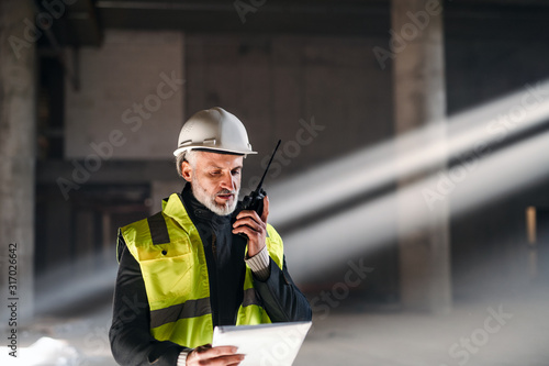 Man engineer using walkie talkie on construction site. photo