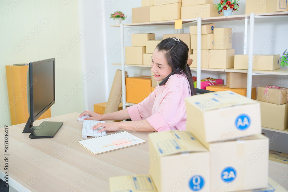 Young business start up online seller owner using computer for checking the customer orders from email or website and preparing packages for product office equipment. Young business start up online seller owner using computer for checking the customer orders from email or website and preparing packages for product office equipment.