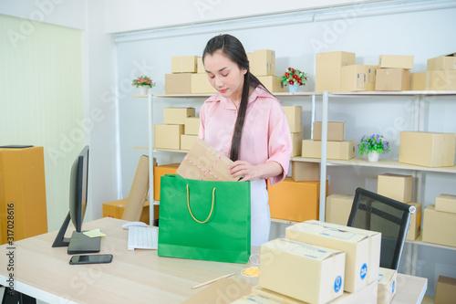 Young asian teenager owner business woman work at home for online shopping, checking order and prepaing package © 2B