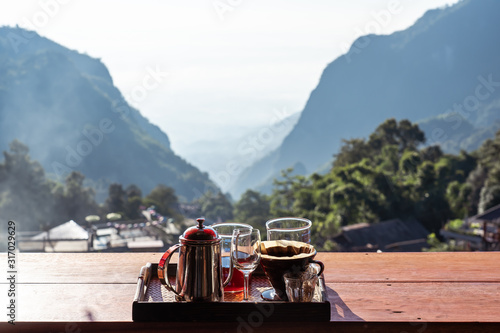 Image of Coffee drip set on wooden table with beautiful landscape mountain heart shape at Coffee Pha Hee, Chiang rai Thailand photo