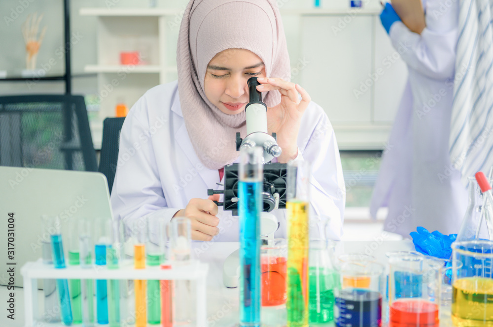 Lab worker. Positive muslim woman looking into the microscope while being at work in the lab Lab worker. Positive muslim woman looking into the microscope while being at work in the lab