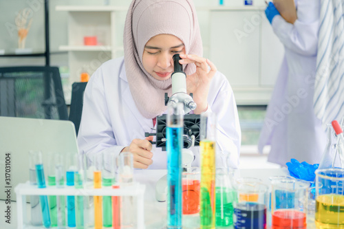 Lab worker. Positive muslim woman looking into the microscope while being at work in the lab