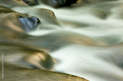 Spring landscape of the Oconaluftee River captured with motion blur and illuminated by reflected color from sunlit foliage  Great Smoky Mountains National Park  North Carolina  USA