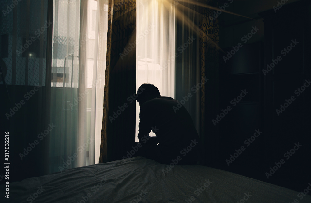 Sad young man sitting on the bed in the bedroom, People with depression concept.