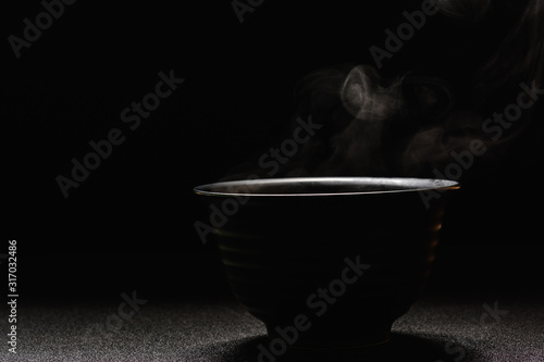 Soup hot in black bowl on wooden table,food steam and copy space ,selective focus.Fresh foods concept