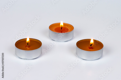 Three burning scented candle in a metal case on a white background.