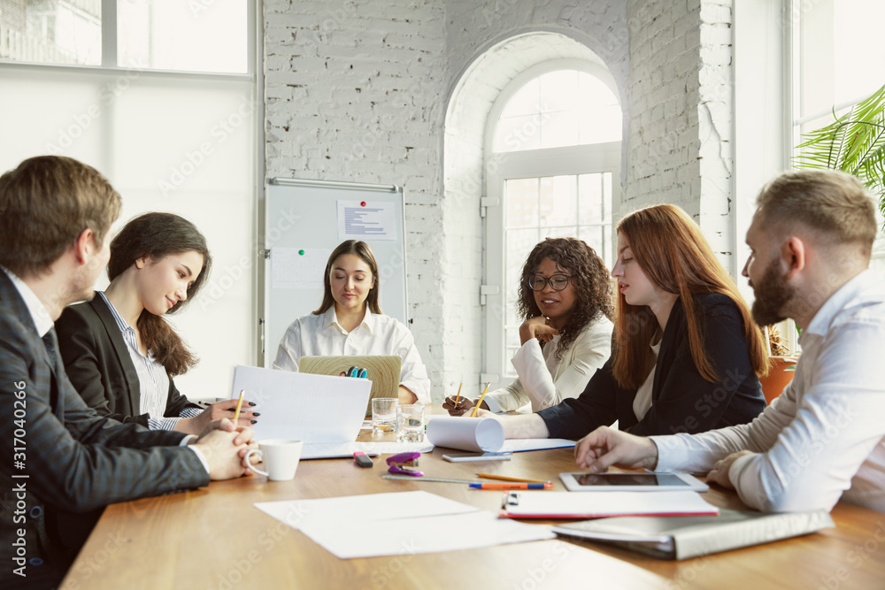 New ideas. Group of young business professionals having a meeting. Diverse group of coworkers discuss new decisions, plans, results, strategy. Creativity, workplace, business, finance, teamwork.