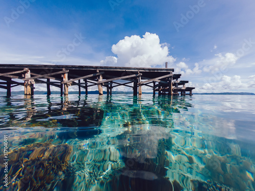 Beautiful landscape of crystal waterline and wooden pier on Maldive island for summer holidays, picturesque oceania view near coastline with marine reflection of Raja Ampat shallow in New Guinea