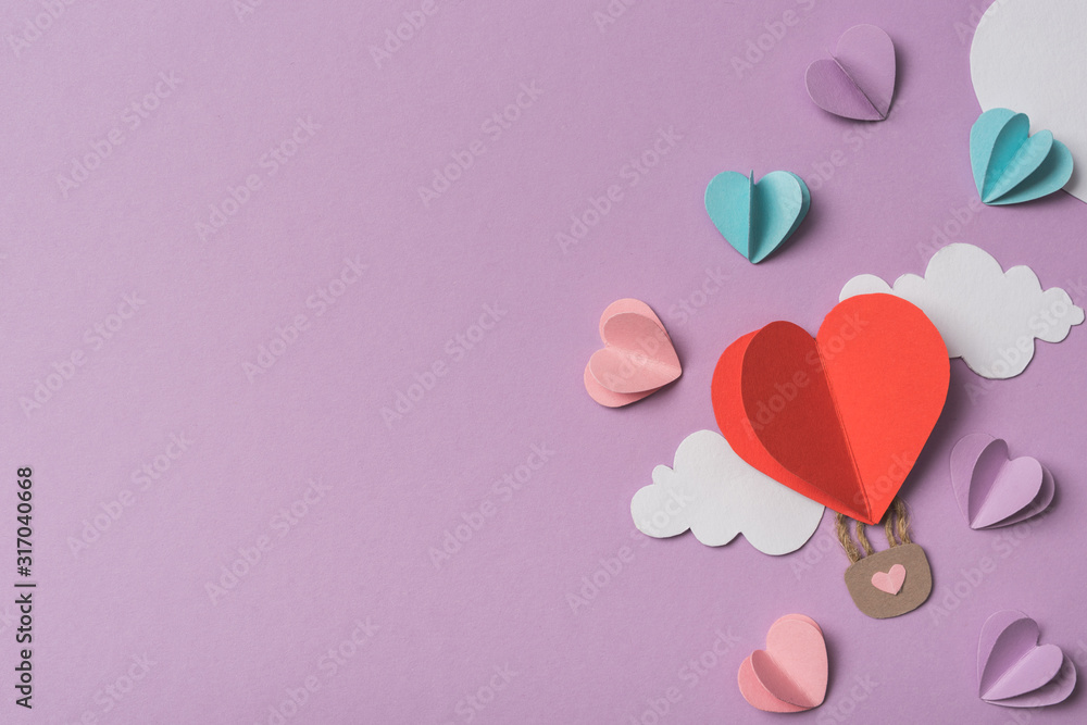 top view of colorful paper hearts and clouds around heart shaped paper air balloon on violet background