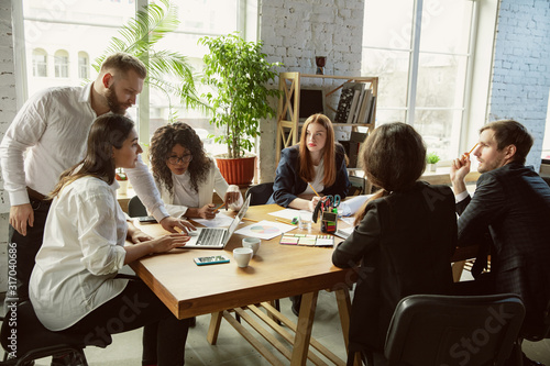 New ideas. Group of young business professionals having a meeting. Diverse group of coworkers discuss new decisions, plans, results, strategy. Creativity, workplace, business, finance, teamwork.