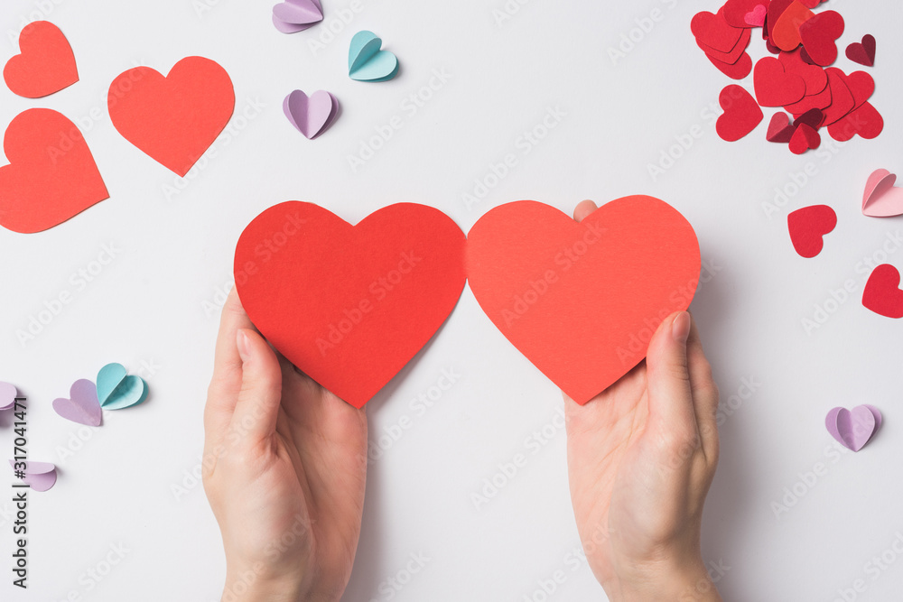 partial view of woman holding blank red heart shaped hearts on white background partial view of woman holding blank red heart shaped hearts on white background