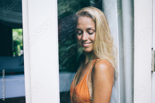 Cheerful flirty young attractive woman standing at glass door