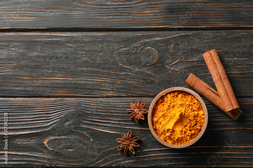 Wood bowl with turmeric and cinnamon on wooden background, top view