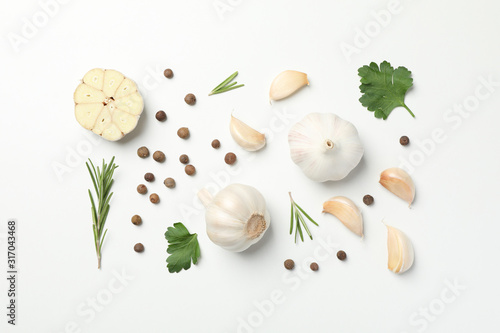 Flat lay of composition, garlic bulbs, slices, spice, parsley, rosemary on white background, top view. Space for text photo