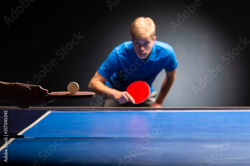 Table tennis ping pong paddles and white ball on blue board © Vesna