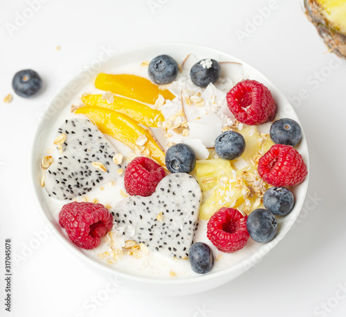 Smoothie bowl with mango, pineapple, dragon fruit, blueberries, raspberries and coconut. Delicious and healthy Breakfast.