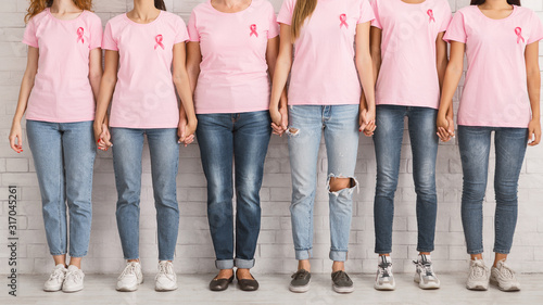 Unrecognizable Women In Pink T-Shirts Holding Hands Standing Near Wall