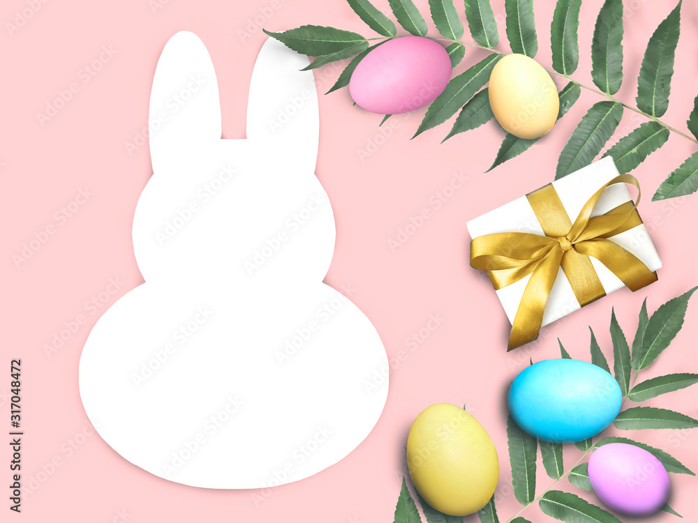 Happy Easter mock card with bunny rabbit frame, multicolor eggs, palm leaves and gift box on pink background. Greeting holiday concept with copyspace.