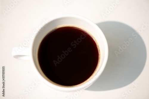 A white cup and black coffee on table