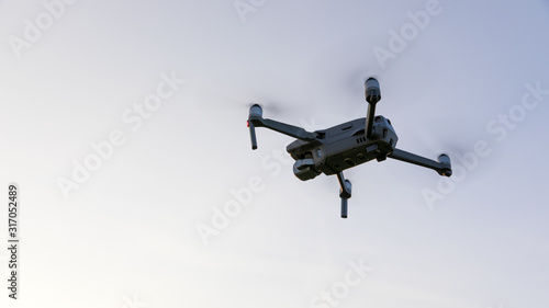 Drone flying over landscape. UAV drone copter flying with digital camera. Drone flying overhead in cloudy blue sky. Quad copter is flying over the field.