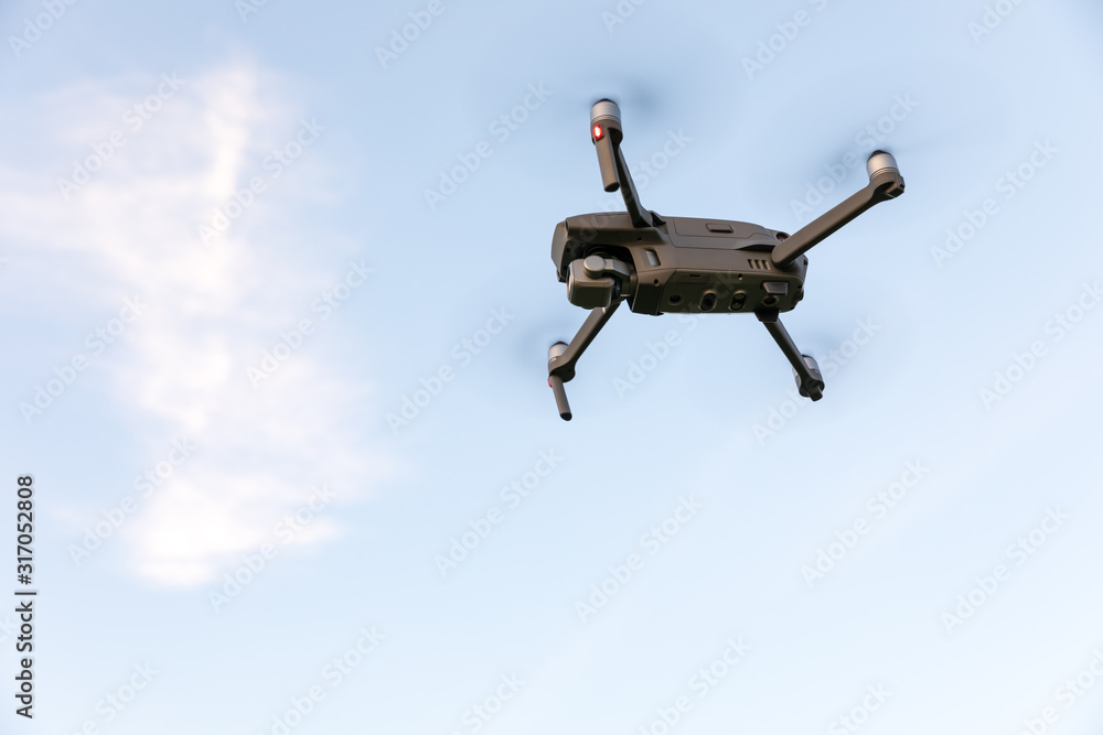 Drone flying over landscape. UAV drone copter flying with digital camera. Drone flying overhead in cloudy blue sky. Quad copter is flying over the field. Drone flying over landscape. UAV drone copter flying with digital camera. Drone flying overhead in cloudy blue sky. Quad copter is flying over the field.