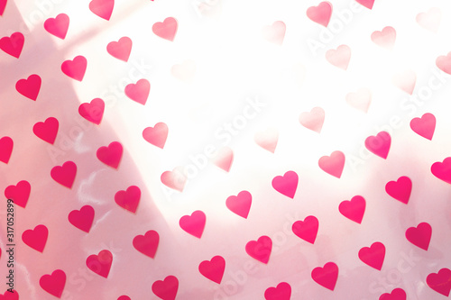 Pattern made of hearts on pink background with sun glare. Abstract love, St. Valentine's day backdrop. Top view, soft focus.