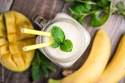 Delicious mango smoothie in mason jar on a rustic background. Healthy food, detox diet. Copy space..