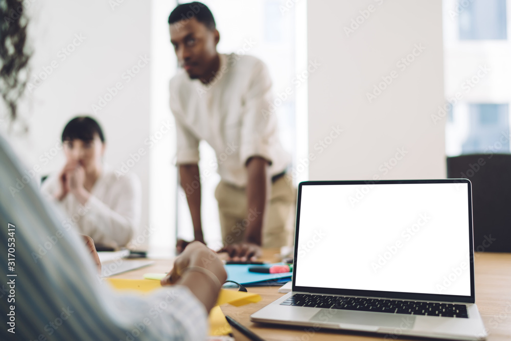 Office employees talking near laptop with empty screen Office employees talking near laptop with empty screen