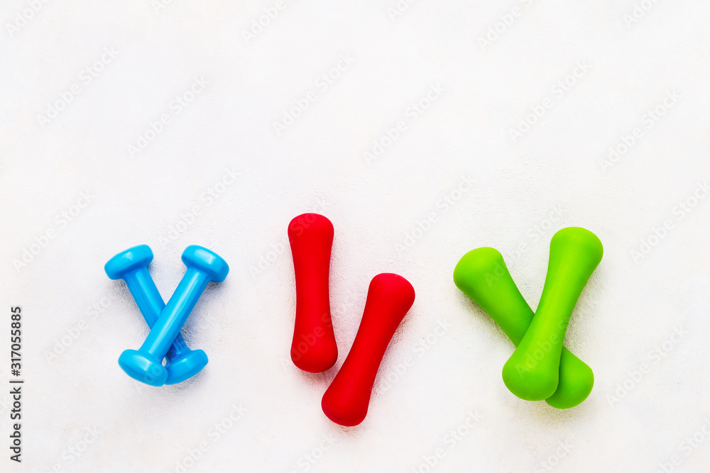 Naklejka premium Colorful dumbbells lie on concrete background. The concept of healthy lifestyle. Copy space, top view