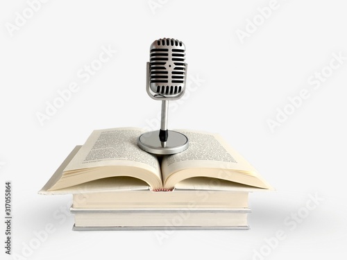 Retro microphone standing on top of opened book. Podcast and audio book concept on white background.