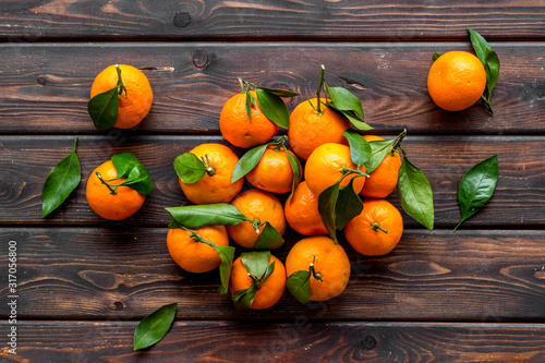 Tangerines with leaves on dark wooden background top-down