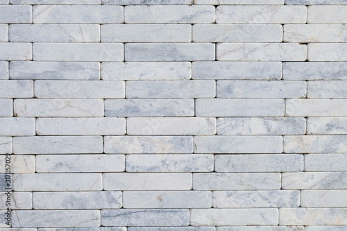 White natural stone marble brick masonry wall outside of the building. Rough surface texture exterior of stone wall. Design and decoration concept with copy space for text.
